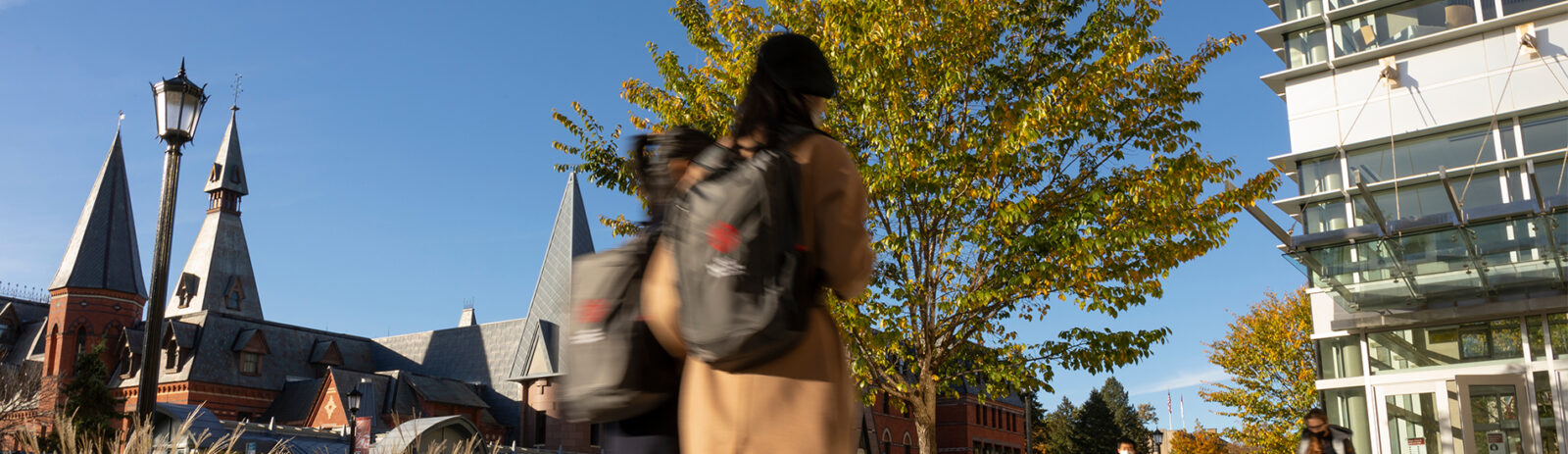Two students with backpacks walk across the quad with Sage Hall and Statler Hall in the background.