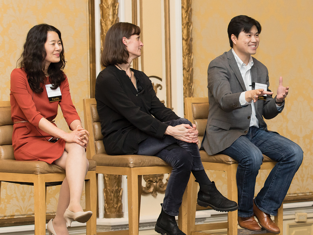 Three people sit on high-top chairs as part of a panel.